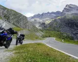 Dwa motocykle czekają na przygodę na krętej drodze przez alpejskie krajobrazy. Idealne trasy motocyklowe Austria!