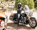 Mężczyzna na czarnym motocyklu Harley-Davidson, wyposażonym w gmole, gotowy na podróż.