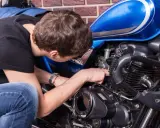 Mężczyzna naprawia niebieski motocykl. Czy to CBS?
