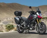 Suzuki DL 1000 V-Strom z kuframi, gotowy na przygodę na krętej drodze pośród pustynnych wzgórz.