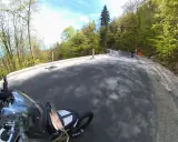Motocyklista pokonuje zakręty najbardziej krętej drogi w Polsce, otoczonej bujną zielenią lasu.