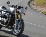 Srebrny Triumph Thruxton 900 na krętej drodze, gotowy na triumfalną jazdę.