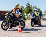 Nauka jazdy na motocyklu. Kursant w kamizelce z literą "L" i kasku na motocyklu, gotowy do zdobycia prawko na motocykl.