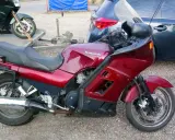 Czerwony motocykl Kawasaki GTR 1000 na przyczepce, obok ciemny samochód.