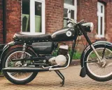 Czarny motocykl wsk 125 na tle ceglanego budynku. Klasyk z PRL-u gotowy do jazdy.