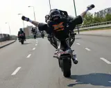 Motocyklista wykonuje jazdę na jednym kole z nogami w powietrzu. Ryzykowne wyczyny mogą skończyć się mandatem.