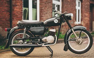 Czarny motocykl wsk 125 na tle ceglanego budynku. Klasyk z PRL-u gotowy do jazdy.