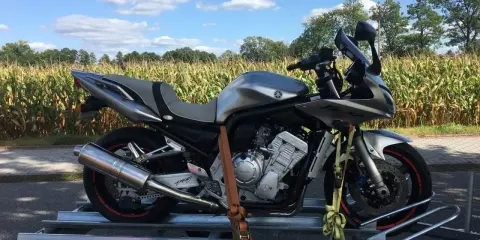 Srebrny motocykl na przyczepce, gotowy do transportu. Może to być związane z akcyzą na motocykle, która wpływa na koszty zakupu.