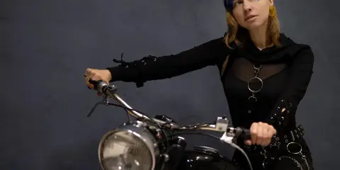 Kobieta na motocyklu, gotowa na odkrywanie tras motocyklowych zachodniopomorskie. Stylowy strój i pewność siebie.