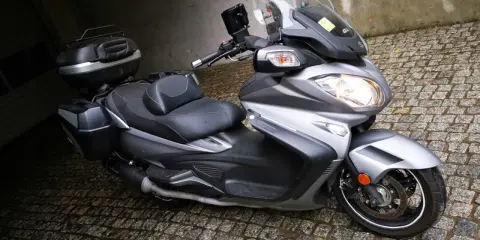 Srebrny Suzuki Burgman 650 z kuframi, gotowy do podróży. Czy są jakieś wady?