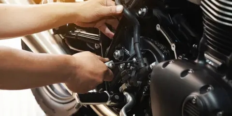 Mechanik dokręca śrubę kluczem imbusowym przy silniku motocykla. Pamiętaj, co ile wymieniac płyn chłodniczy, by uniknąć przegrzania.