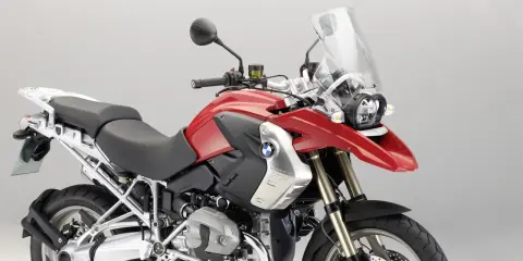 Czerwony motocykl BMW R1200GS z czarnym siedzeniem i dużą szybą.