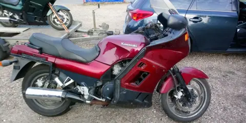 Czerwony motocykl Kawasaki GTR 1000 na przyczepce, obok ciemny samochód.