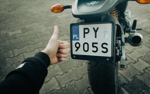 Kciuk w górę przy rejestracji starego motocykla z dokumentami. PY 905S.