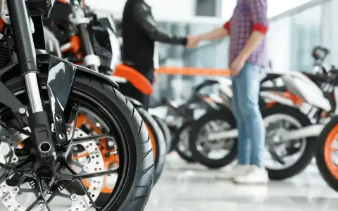 Dwóch mężczyzn ściska sobie dłonie przy motocyklach. Sfinalizowali sprzedaż motocykla przed upływem 6 miesięcy.