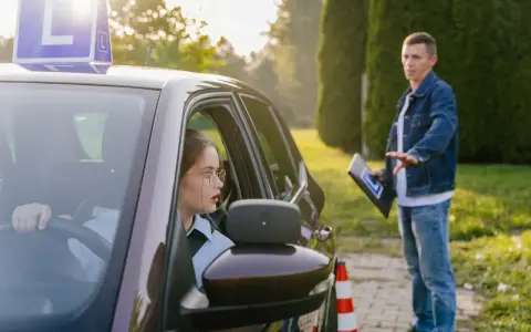 Młoda kursantka za kierownicą, instruktor objaśnia zasady. Zastanawia się, ile jest ważny egzamin teoretyczny na prawo jazdy.