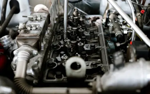 Wnętrze silnika z widocznymi zaworami i wtryskiwaczami. Mechanik sprawdza, czy nie występuje co to jest spalanie stukowe, które może uszkodzić jednostkę.
