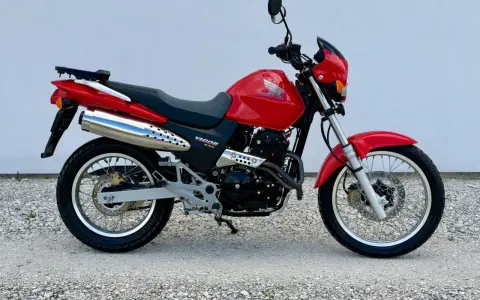 Czerwony Honda Dominator 650 Vigor. Wady i zalety tego motocykla to m.in. jego wszechstronność i prostota konstrukcji.