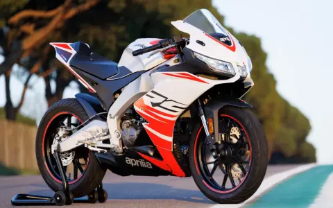 Sportowy motocykl Aprilia RS 125 2T, biało-czerwony, z widocznymi detalami i napisem "RS". Idealny do poznania jego aprilia rs 125 2t dane techniczne.