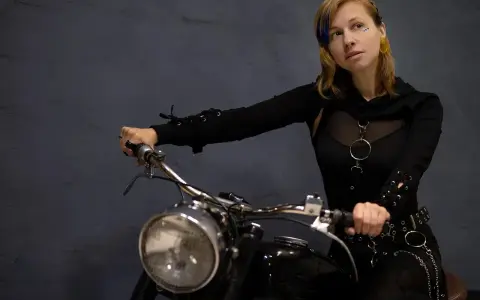 Kobieta na motocyklu, gotowa na odkrywanie tras motocyklowych zachodniopomorskie. Stylowy strój i pewność siebie.