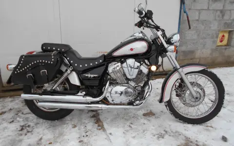 Czarny motocykl Zipp Roadstar 250 z sakwami, błyszczącymi chromami i ozdobnymi nitami, stoi na zaśnieżonym podjeździe.