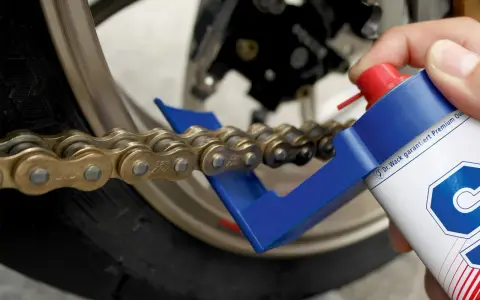 Czyszczenie i smarowanie łańcucha motocyklowego. Specjalny aplikator ułatwia dotarcie do wszystkich ogniw, pomagając w utrzymaniu napędu w idealnym stanie.