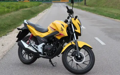 Żółty motocykl Honda CBF 125F na drodze. Poznaj honda cbf 125 dane techniczne i możliwości tego zwinnego jednośladu.
