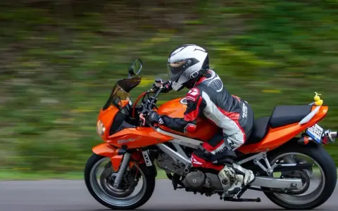 Motocyklista w kombinezonie śmiga pomarańczowym motocyklem. Idealna trasa motocyklowa Śląsk na weekendową przejażdżkę.