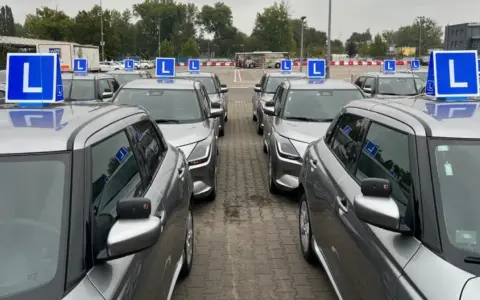 Rząd srebrnych aut z niebieskimi literami "L" na dachach. Czekają na kursantów, którzy zdali teorię i chcą jak najszybciej zdać praktykę.