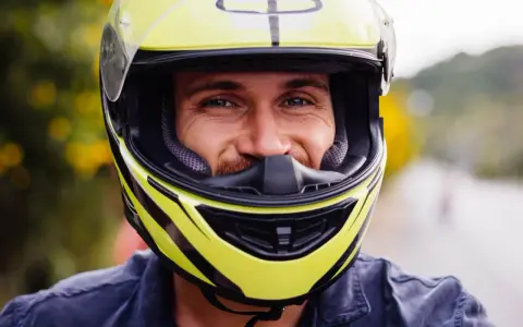 Uśmiechnięty mężczyzna w żółtym kasku motocyklowym. Dobór odpowiednich rozmiarów kasków motocyklowych to klucz do bezpieczeństwa.