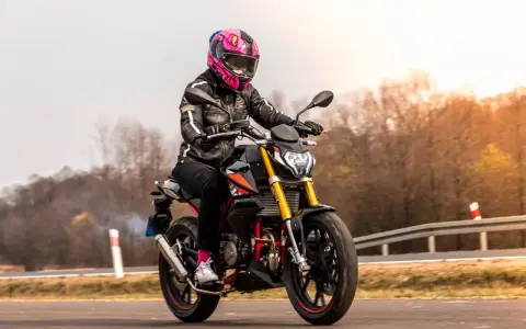 Motocyklistka w kolorowym kasku pędzi na czarnym motocyklu. Zastanawiasz się, ile waży litr benzyny, gdy tankujesz przed podróżą?