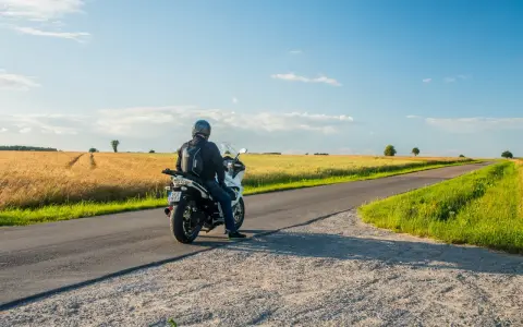 Motocyklista na tle pól pszenicy, odkrywa malownicze trasy motocyklowe mazowieckie.