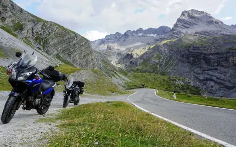 Dwa motocykle czekają na przygodę na krętej drodze przez alpejskie krajobrazy. Idealne trasy motocyklowe Austria!