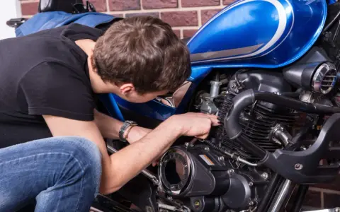 Mężczyzna naprawia niebieski motocykl. Czy to CBS?