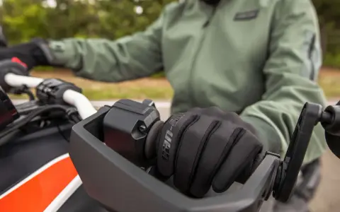Rękawiczka motocyklisty na kierownicy. Dowiedz się, jak sprawdzić żywotność akumulatora, by zawsze ruszyć w drogę.