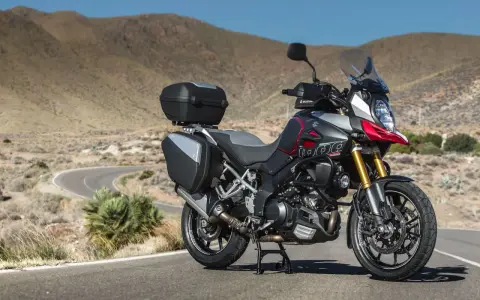 Suzuki DL 1000 V-Strom z kuframi, gotowy na przygodę na krętej drodze pośród pustynnych wzgórz.