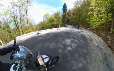 Motocyklista pokonuje zakręty najbardziej krętej drogi w Polsce, otoczonej bujną zielenią lasu.