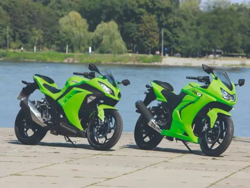 Dwa zielone Kawasaki Ninja 250 stoją nad wodą. Poznaj kawasaki ninja 250 dane techniczne i poczuj moc!
