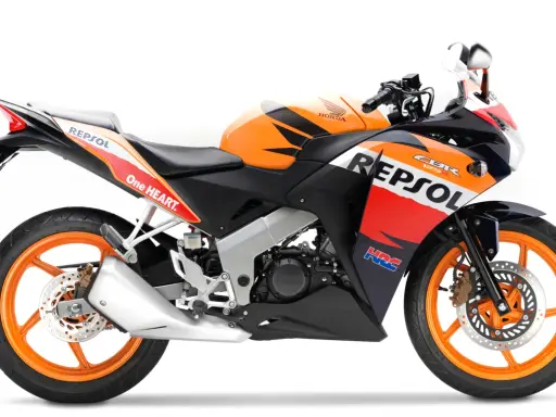 Pomarańczowo-czarny motocykl Honda CBR 125R w barwach Repsol, gotowy do jazdy z mocą V-max.