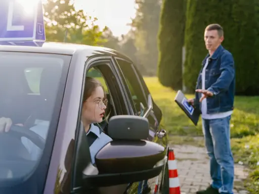 Młoda kursantka za kierownicą, instruktor objaśnia zasady. Zastanawia się, ile jest ważny egzamin teoretyczny na prawo jazdy.