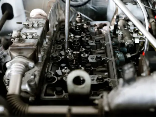Wnętrze silnika z widocznymi zaworami i wtryskiwaczami. Mechanik sprawdza, czy nie występuje co to jest spalanie stukowe, które może uszkodzić jednostkę.