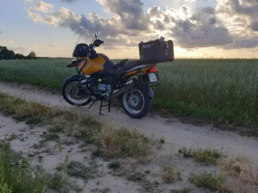 Żółty motocykl turystyczny na piaszczystej drodze wśród pól. Idealne miejsce na odkrywanie tras motocyklowych Kaszuby.