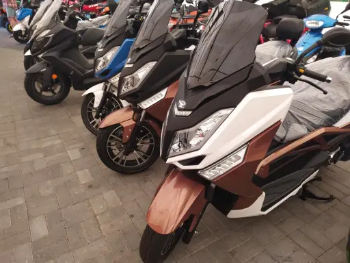 Kilka skuterów, w tym brązowy zipp qr max 125, stoi na chodniku.