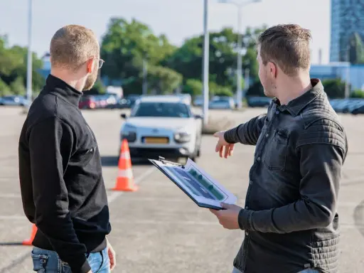 Instruktor omawia z kursantem plan trasy, świętując jego pozytywny wynik egzaminu teoretycznego.