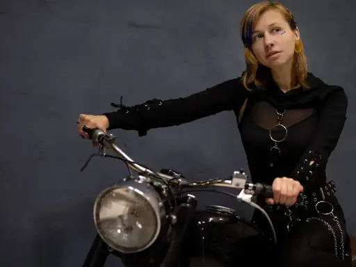Kobieta na motocyklu, gotowa na odkrywanie tras motocyklowych zachodniopomorskie. Stylowy strój i pewność siebie.