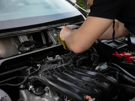 Mechanik sprawdza, dlaczego przekaźnik cyka, a rozrusznik nie kręci. Widok na silnik i przewody.