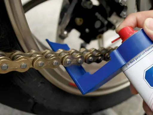 Czyszczenie i smarowanie łańcucha motocyklowego. Specjalny aplikator ułatwia dotarcie do wszystkich ogniw, pomagając w utrzymaniu napędu w idealnym stanie.