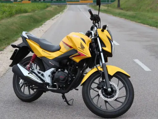 Żółty motocykl Honda CBF 125F na drodze. Poznaj honda cbf 125 dane techniczne i możliwości tego zwinnego jednośladu.