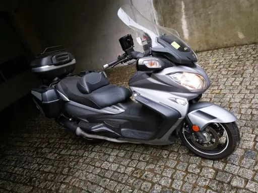 Srebrny Suzuki Burgman 650 z kuframi, gotowy do podróży. Czy są jakieś wady?