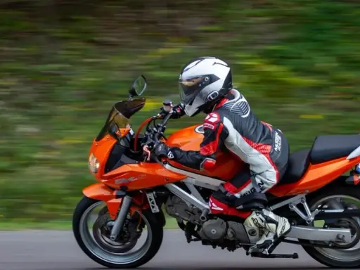 Motocyklista w kombinezonie śmiga pomarańczowym motocyklem. Idealna trasa motocyklowa Śląsk na weekendową przejażdżkę.